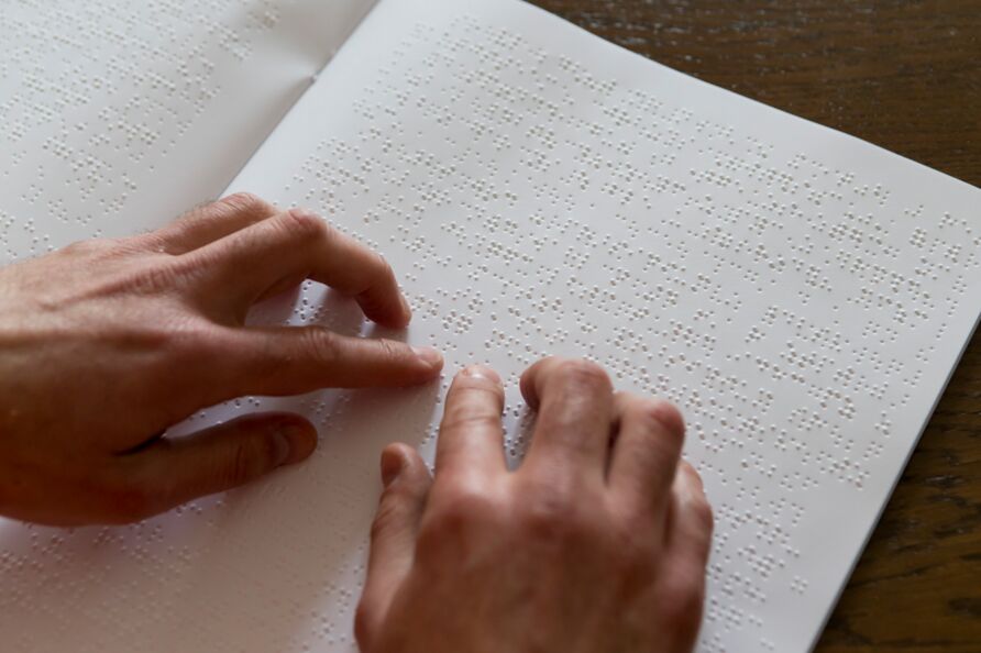 Zwei Hände lesen einen Text in Brailleschrift